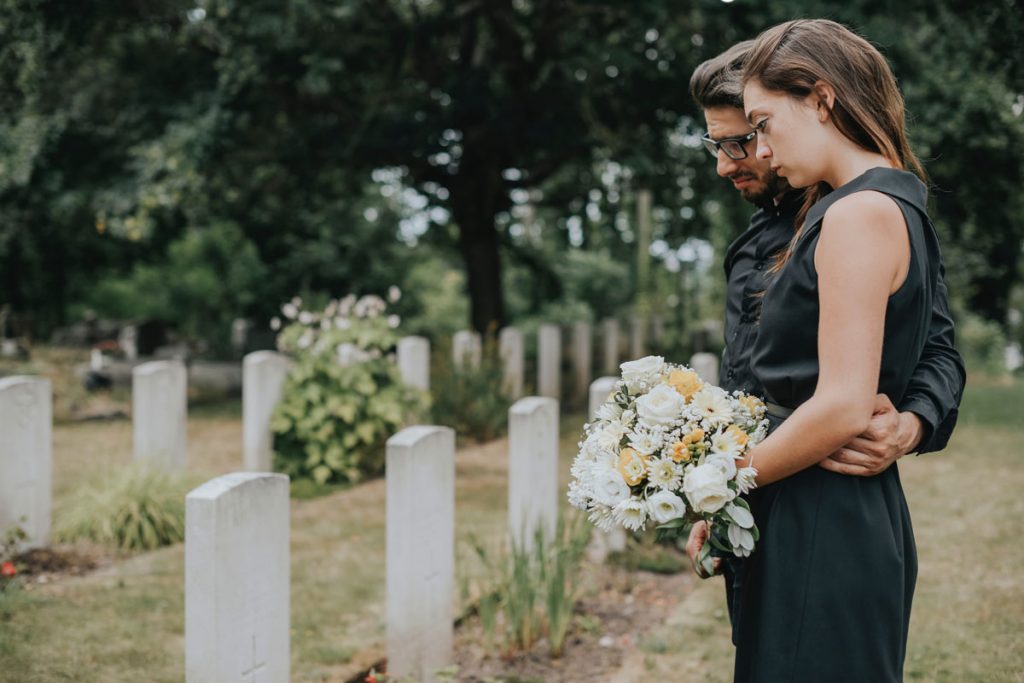 Trauerndes Paar bei der Bestattung eines Angehörigen.